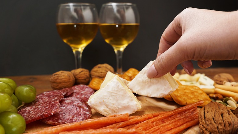 Person grabbing cheese from charcuterie board