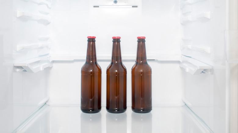 three beer bottles in an empty refrigerator