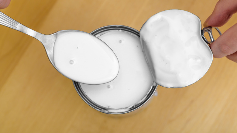 Coconut cream in spoon and can, closeup