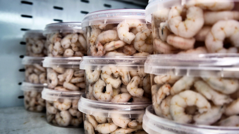 Raw shrimp in containers on a fridge shelf