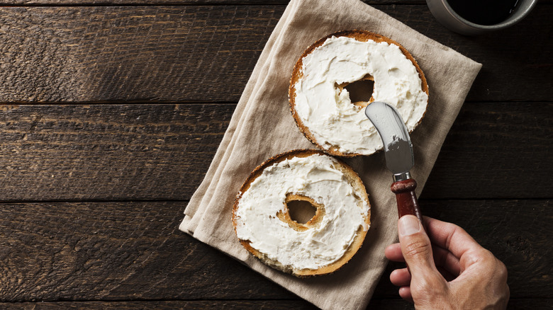 bagel with cream cheese and a knife spreading it