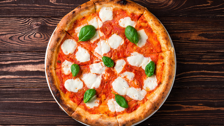 Pizza topped with basil and goat cheese.