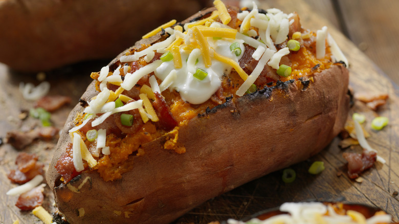 baked potato topped with sour cream, cheese, and green onions