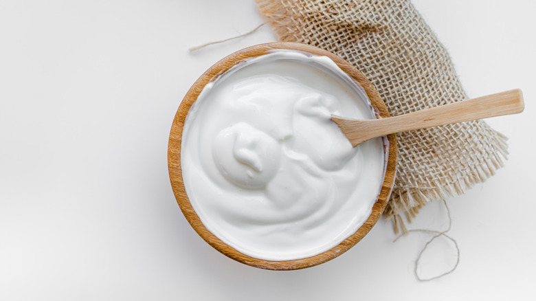 Sour cream in bowl on top of burlap, overhead view.