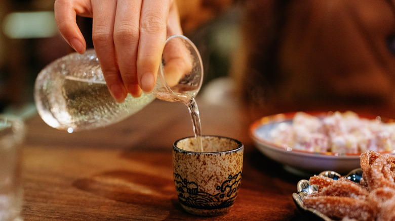 Hand pouring sake into cup