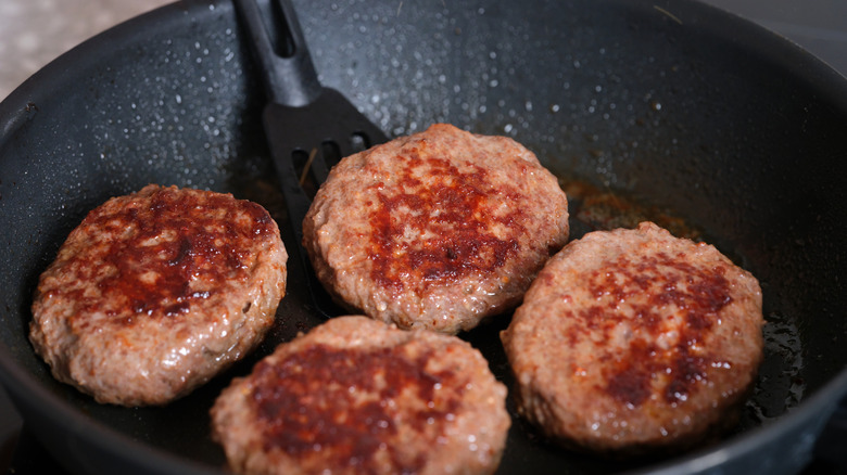 Burgers in a pan with spatula