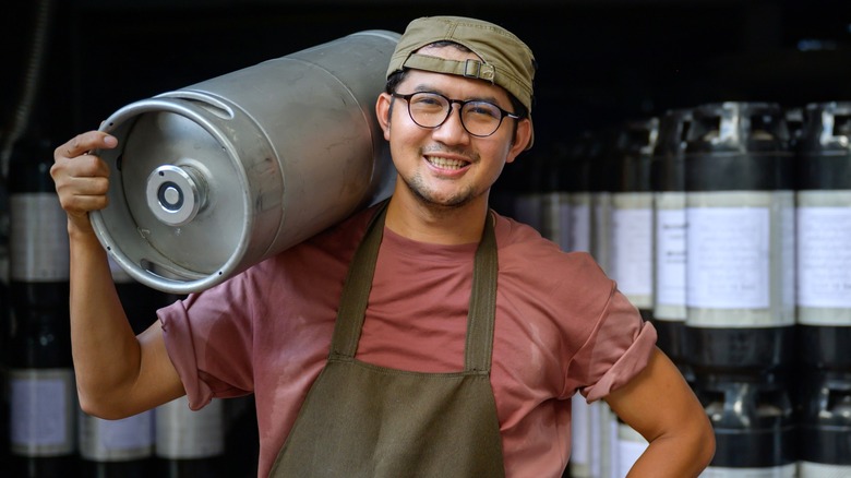 A person holding a small beer keg on their shoulder