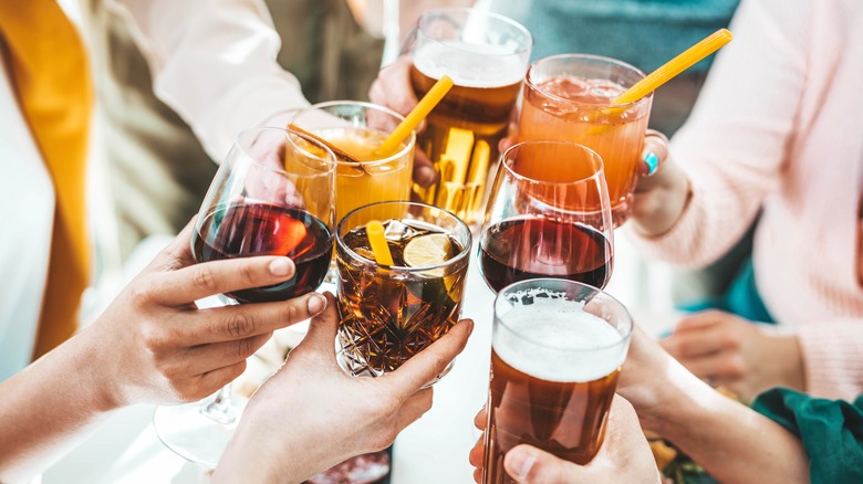 Group holding various mixed drinks, wine, and beer