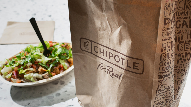 Chipotle paper bag besides a bowl.