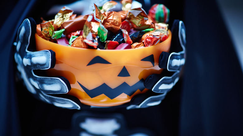 Costumed skeleton hands holding candy bowl