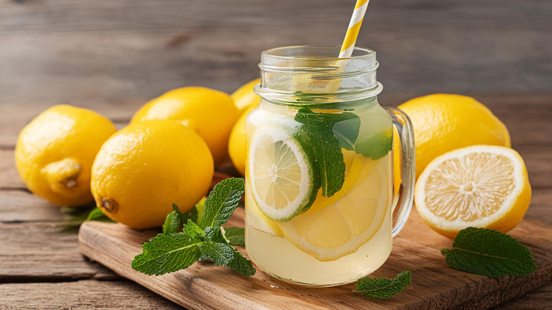 Homemade lemonade in clear glass jar with lemons and mint.