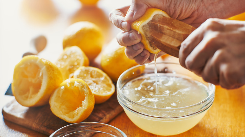 Using a tool to squeeze lemon juice from halved lemons.