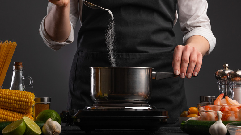 Chef adding salt to pasta water