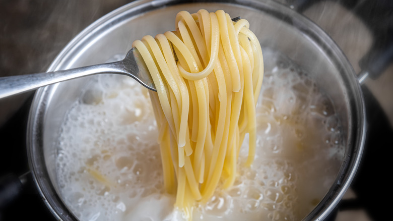 Noodles lifted from boiling pot with fork