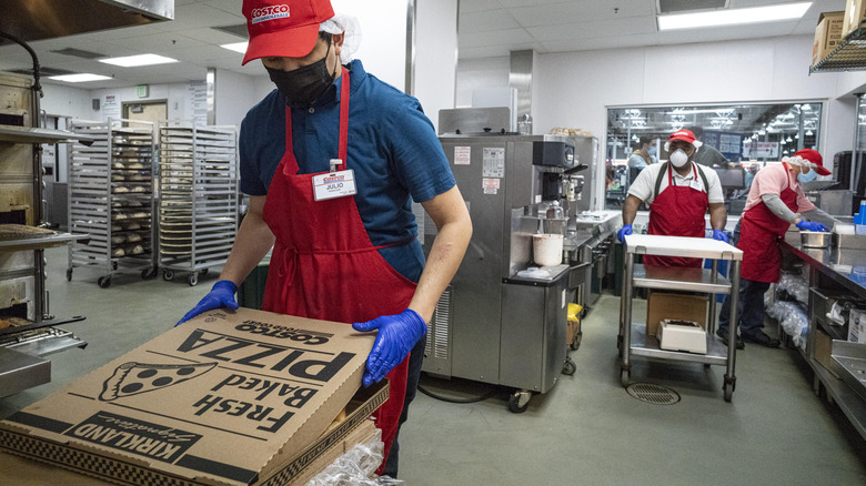 Costco worker boxing a fresh Kirkland pizza