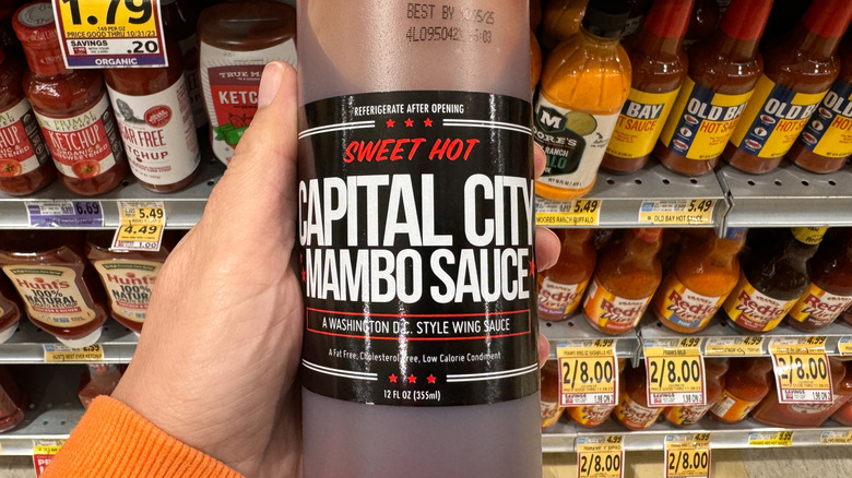 Hand holds up a bottle of Capital City Mambo Sauce.