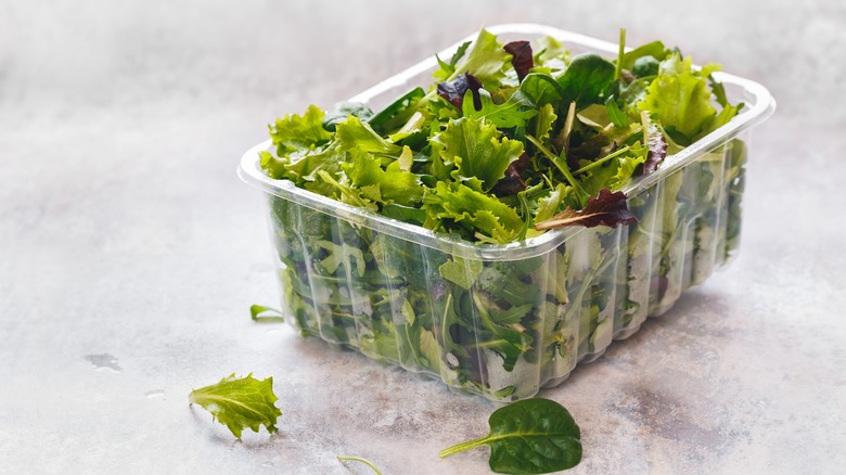 plastic container overflowing with salad leaves
