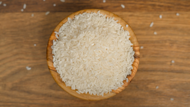 A small wooden bowl filled with uncooked white rice