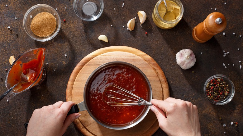 Top view person mixing ingredients into pot with whisk