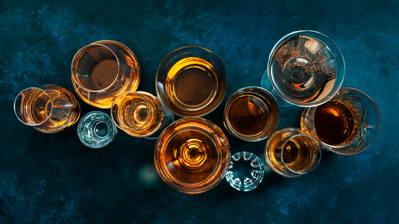 Whiskey in various glasses blue background