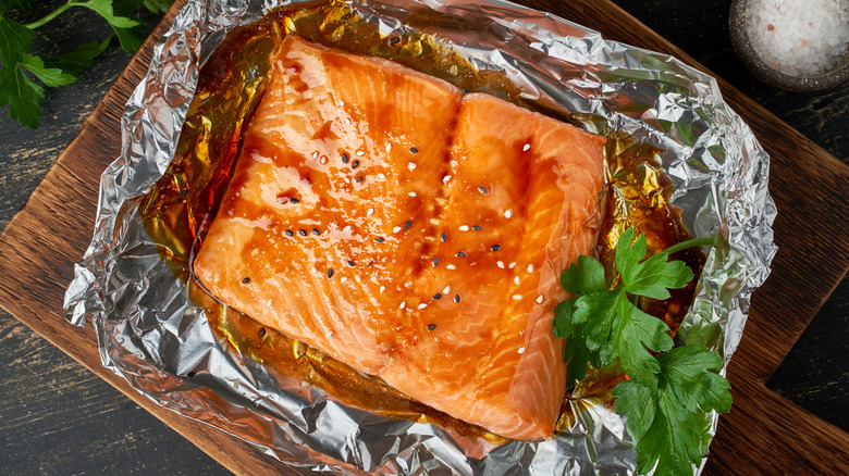 Grilled salmon in foil on wood board