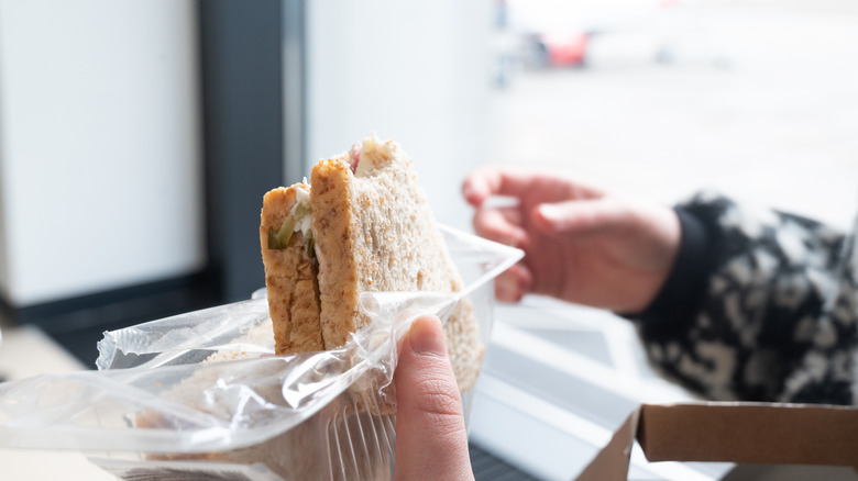 Person holding unwrapped sandwich