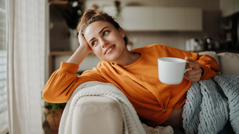 a young woman resting on a sofa with a cup of tea