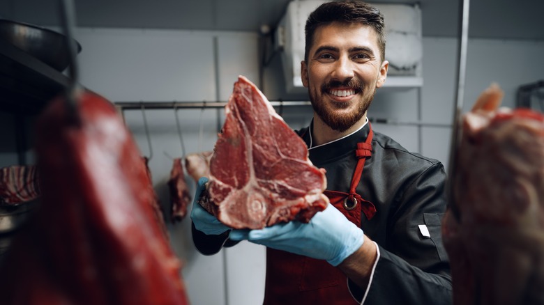 Male butcher holding a piece of raw meat