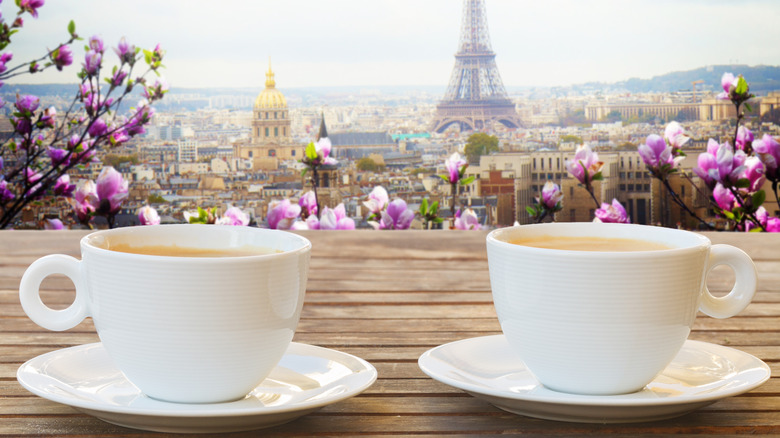 Two cups of coffee with Eifel Tower in background.