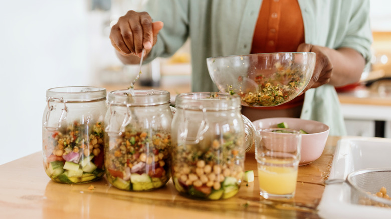 Person meal-prepping salad jars