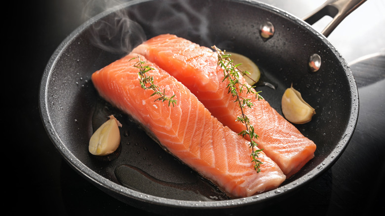 Gently frying salmon fillets in a pan.