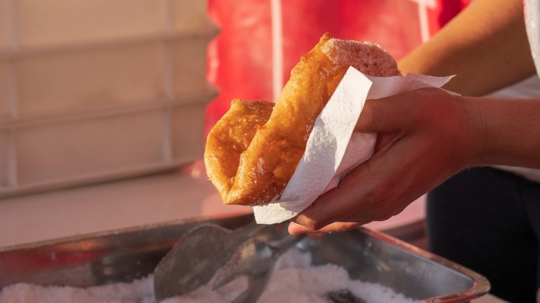 Person handling a pizza fritta in paper