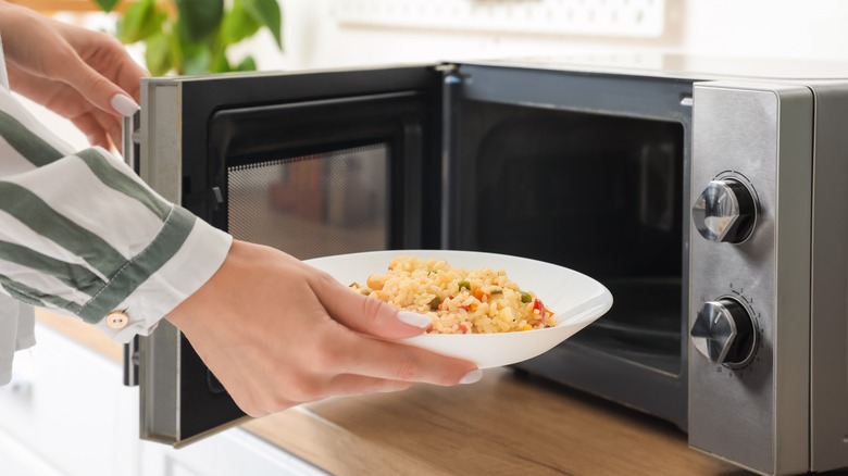 woman reheating bowl of fried rice in microwave