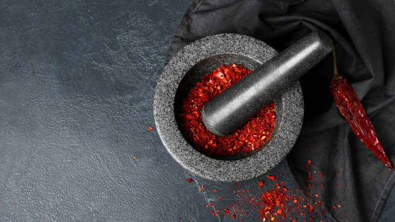 Mortar and pestle with spices on black surface