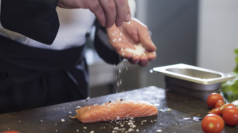 Chef seasoning salmon with salt