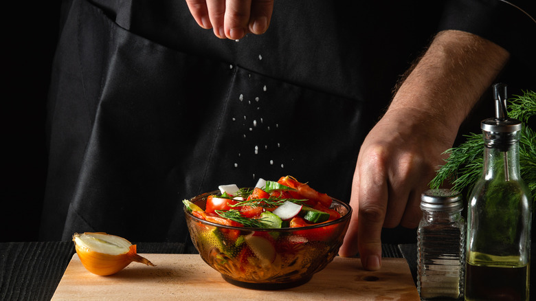 Chef seasoning vegetables in bowl