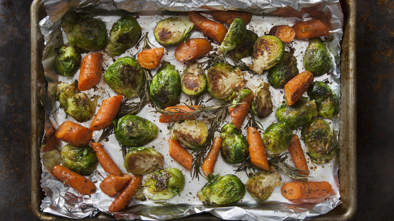 Roasted Brussels sprouts and carrots on a sheet pan with aluminum foil