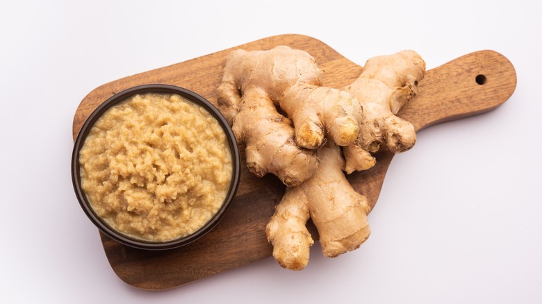 Ginger paste in a bowl on a cutting board with ginger root