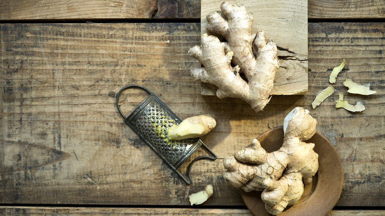 Ginger root on a wooden surface with a small grater