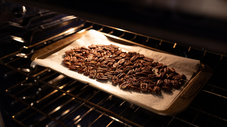 Pecans roasting on a cookie sheet in the oven