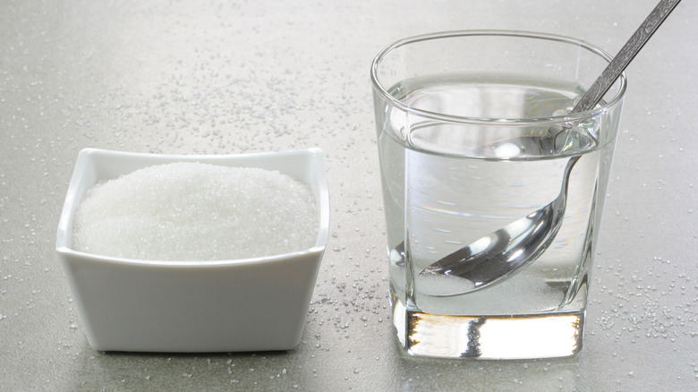 Sugar in white bowl and water in glass