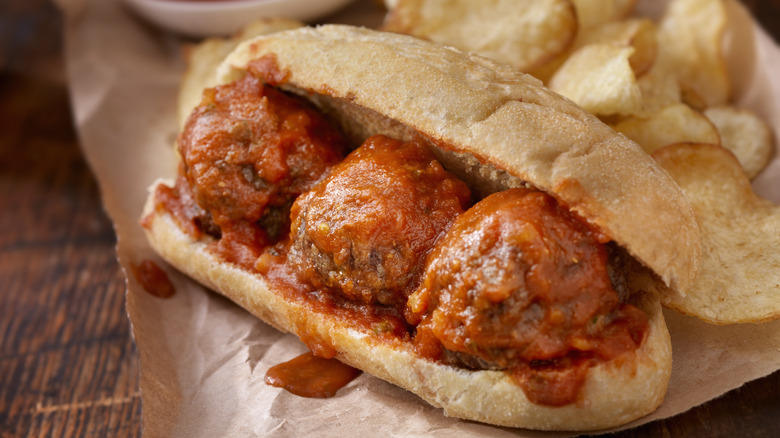 A meatball sub dripping sauce on wax paper