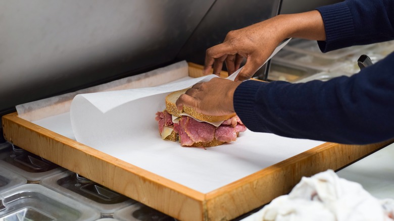 Man wrapping a sandwich with parchment paper