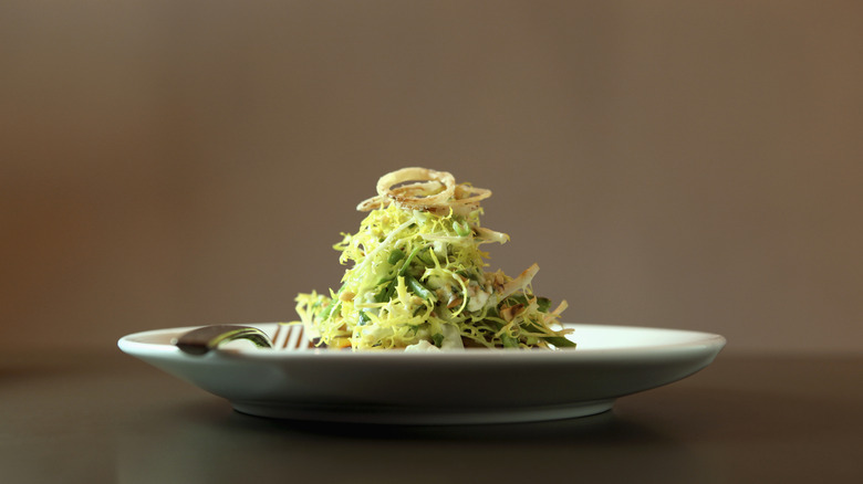 Tall plated salad on white dish with fork