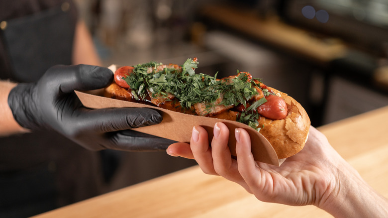 Chef hands a hot dog to a customer