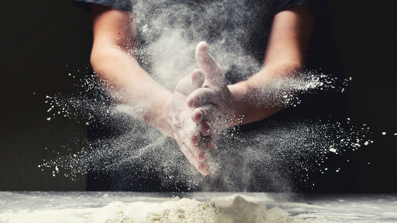 Person clapping hands together and spreading flour