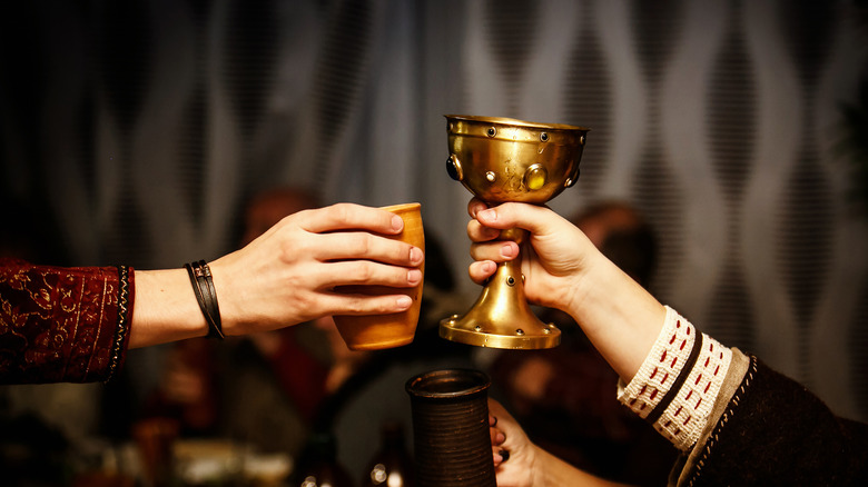 people raising a cup and a chalice at a medieval feast