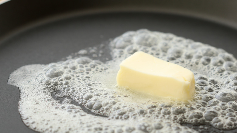 Butter melting in dark skillet closeup.