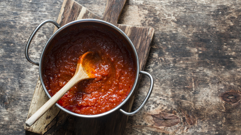 Tomato sauce in pan on wooden cutting board