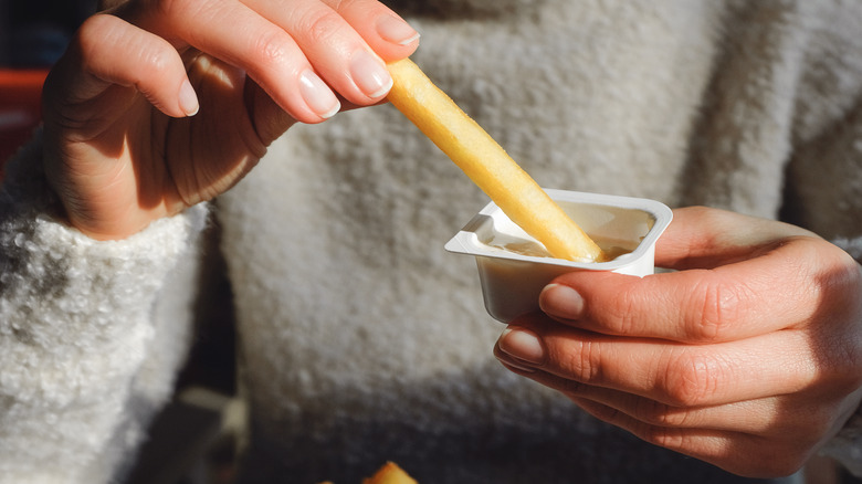 Person dipping fries in sauce